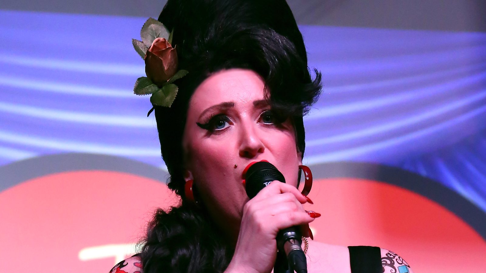 Close-up of the lead vocalist singing into the microphone, in Amy Winehouse beehive and winged eyeliner